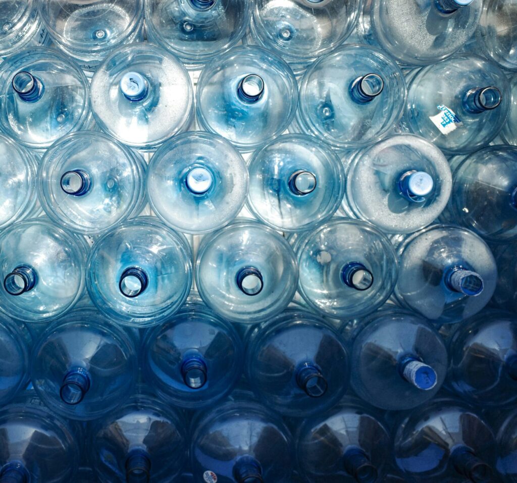 A large stack of 5 gallon water jugs