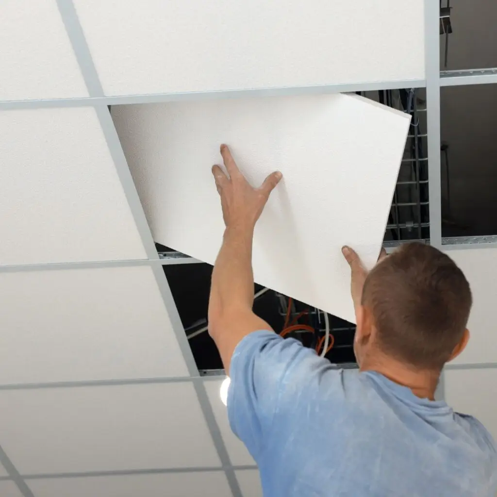 Technician running water line through ceiling tile