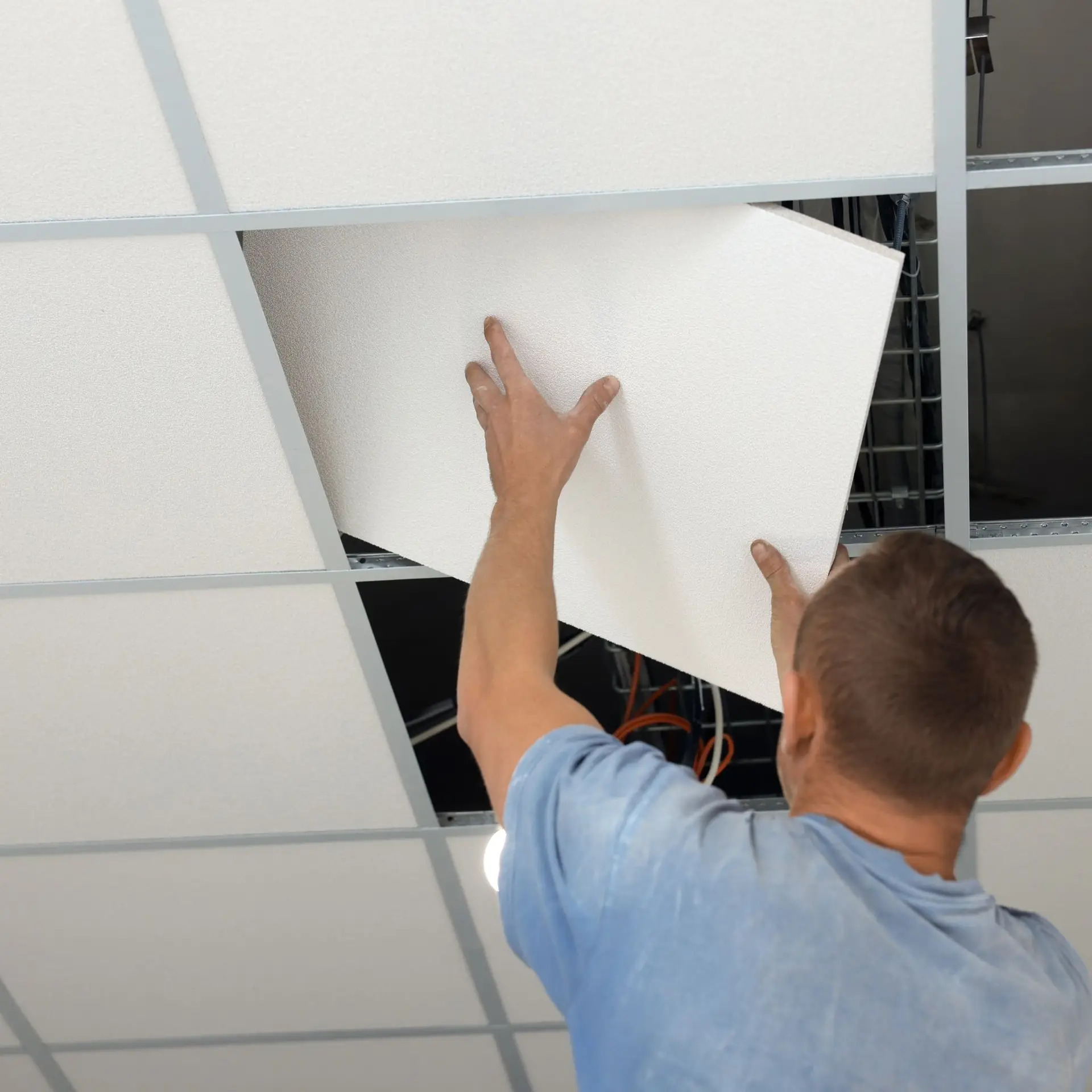 Technician running water line through ceiling tile